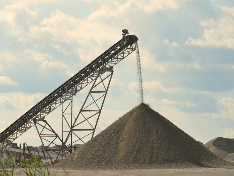 Conveyor belt dropping material onto a conical stockpile at a gravel pit — stock photo