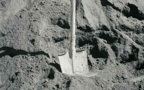 Heap of fine grey sand with a shovel — stock photo
