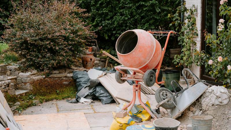 Small cement mixer with building materials on a patio